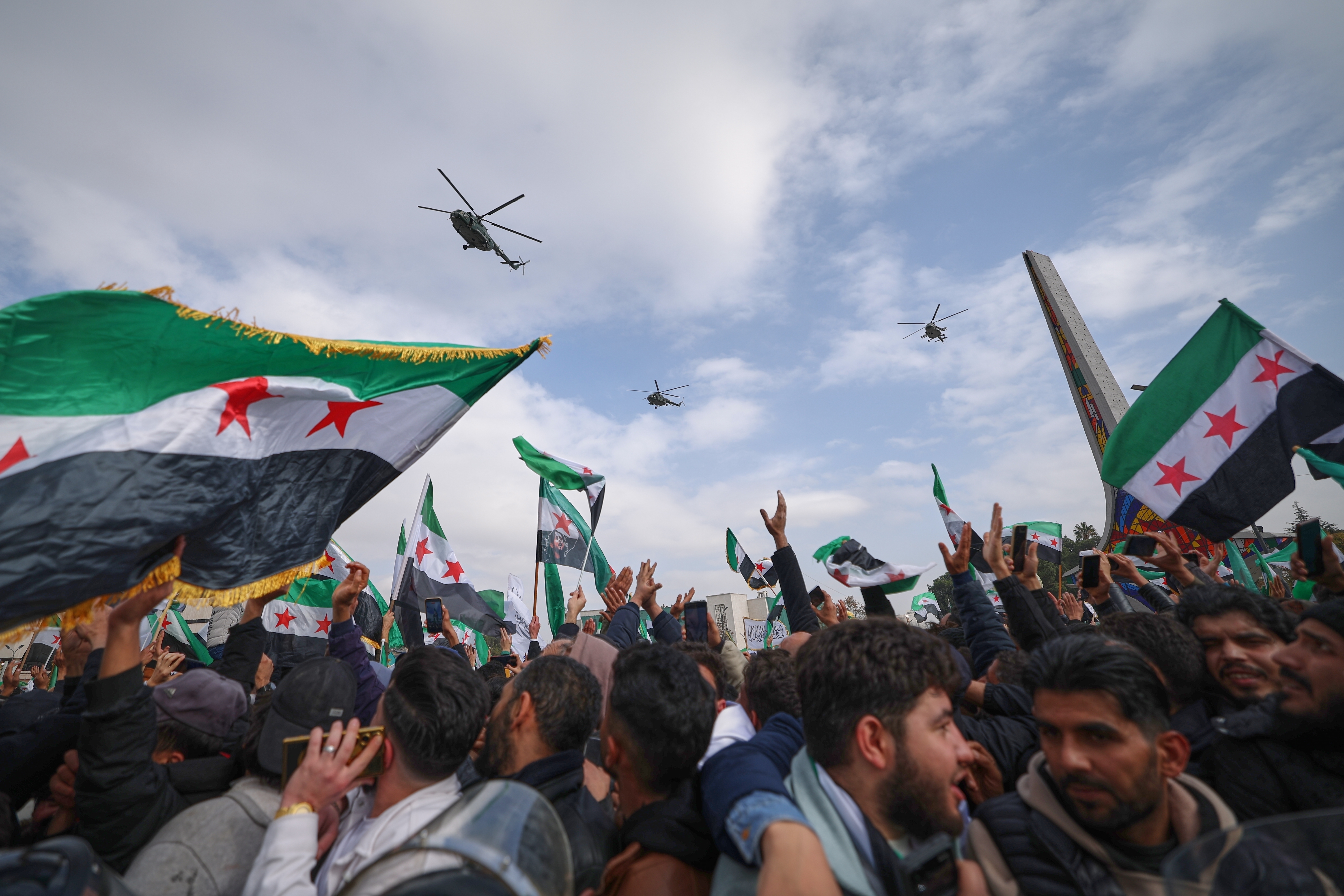 Army helicopters fly overhead during a parade by the new Syrian army marking the first anniversary of the ousting of the Bashar Assad regime in Damascus, Syria, Monday.